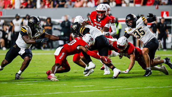 Sep 26, 2026; Raleigh, North Carolina, USA;  App State Mountaineers quarterback Malachi Singleton (3) is tackled by multiple NC State Wolfpack players during the first half of the game at Carter-Finley Stadium.  Mandatory Credit: Jaylynn Nash-Imagn Images