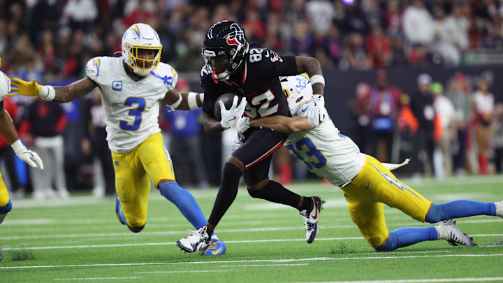 Jan 11, 2025; Houston, Texas, USA; Houston Texans wide receiver Diontae Johnson (82) runs the ball after a reception against Los Angeles Chargers defensive back Deane Leonard (33) and safety Derwin Jarnes Jr. (3) during the third quarter in an AFC wild card game at NRG Stadium. Mandatory Credit: Troy Taormina-Imagn Images