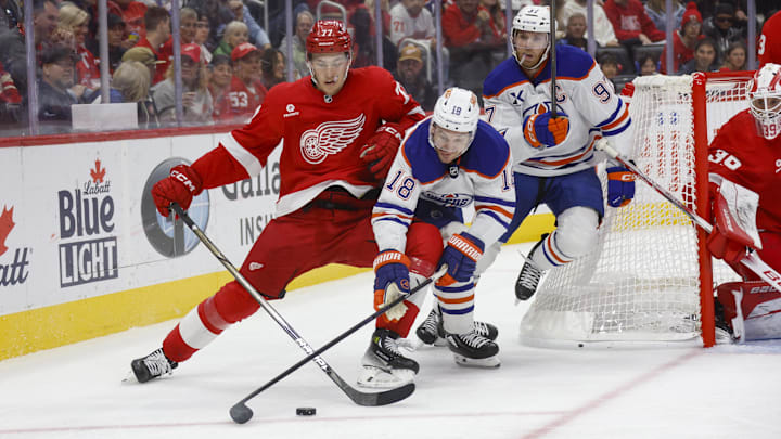 Oct 27, 2024; Detroit, Michigan, USA; Detroit Red Wings defenseman Simon Edvinsson (77) fights for control of the puck against Edmonton Oilers left wing Zach Hyman (18) during the third period at Little Caesars Arena. Mandatory Credit: Brian Bradshaw Sevald-Imagn Images