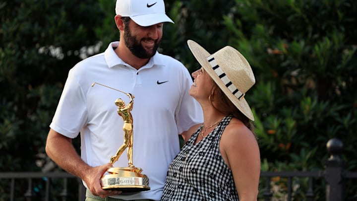 Scottie Scheffler looks to his wife Meredith Scudder as he poses for photos with the championship trophy after the fourth and final round of The Players Championship PGA golf tournament Sunday, March 17, 2024 at TPC Sawgrass.