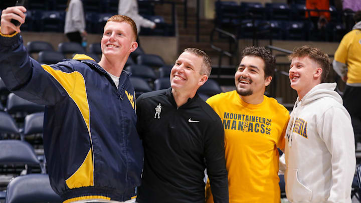 Nov 30, 2025; Morgantown, West Virginia, USA; West Virginia Mountaineers head coach Ross Hodge poses for a photo with students after defeating the Mercyhurst Lakers at Hope Coliseum. Mandatory Credit: Ben Queen-Imagn Images Nov 30, 2025; Morgantown, West Virginia, USA; West Virginia Mountaineers head coach Ross Hodge poses for a photo with students after defeating the Mercyhurst Lakers at Hope Coliseum. Mandatory Credit: Ben Queen-Imagn Images