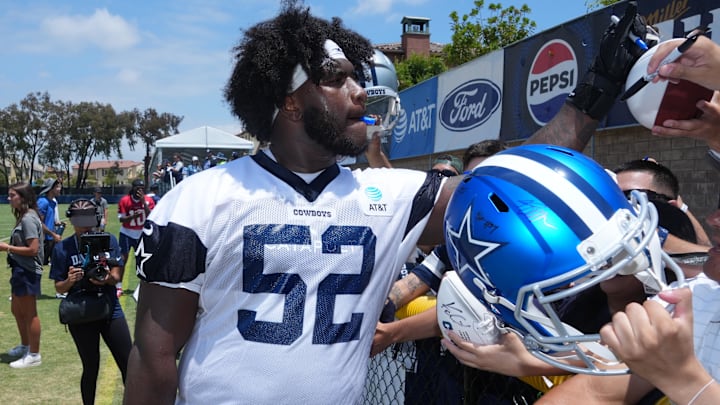 Dallas Cowboys guard Tyler Booker signs autographs during training camp at the River Ridge Fields.