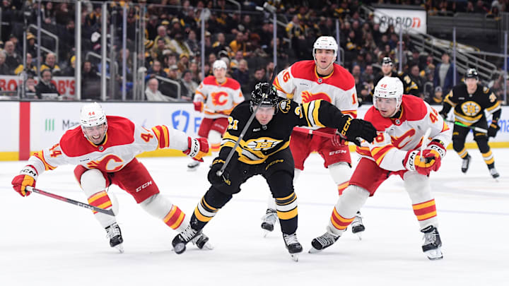 Jan 8, 2026; Boston, Massachusetts, USA; Calgary Flames defenseman Joel Hanley (44) Boston Bruins center Alex Steeves (21) and defenseman Hunter Brzustewicz (48) chase after the during the third period at TD Garden. Mandatory Credit: Bob DeChiara-Imagn Images