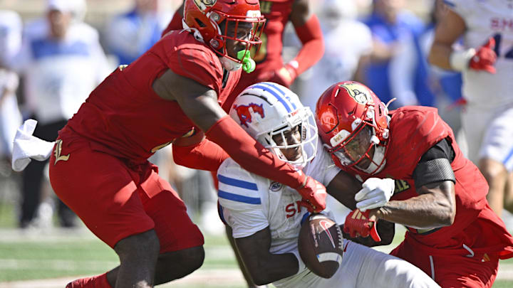 Oct 5, 2024; Louisville, Kentucky, USA;  Louisville Cardinals linebacker Stanquan Clark (6) and defensive back Tamarion McDonald (12) try to strip the ball from Southern Methodist Mustangs running back Brashard Smith (1) during the second half at L&N Federal Credit Union Stadium. Mandatory Credit: Jamie Rhodes-Imagn Images