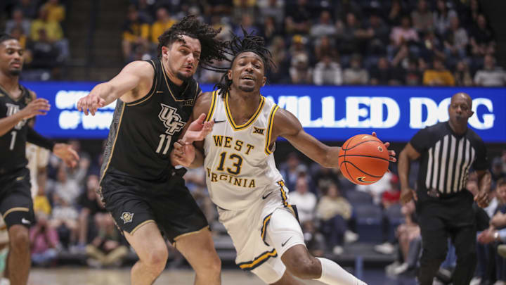 Mar 6, 2026; Morgantown, West Virginia, USA; West Virginia Mountaineers guard Chance Moore (13) dribbles and collides with UCF Knights guard Carmelo Pacheco (11) during the second half at Hope Coliseum. Mandatory Credit: Ben Queen-Imagn Images