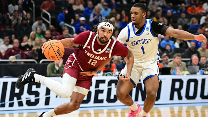 Mar 21, 2025; Milwaukee, WI, USA; Troy Trojans guard Tayton Conerway (12) drives to the hoop past Kentucky Wildcats guard Lamont Butler (1) during the second half at Fiserv Forum. Mandatory Credit: Benny Sieu-Imagn Images