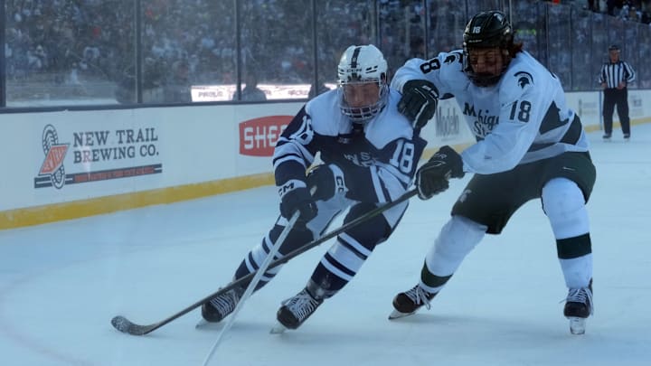 Jan 31, 2026; State College, PA, USA; Penn State Nittany Lions forward Aiden Fink (18) skates with the puck as Michigan State Spartans forward Ryker Lee (18) at Beaver Stadium. Mandatory Credit: James Lang-Imagn Images