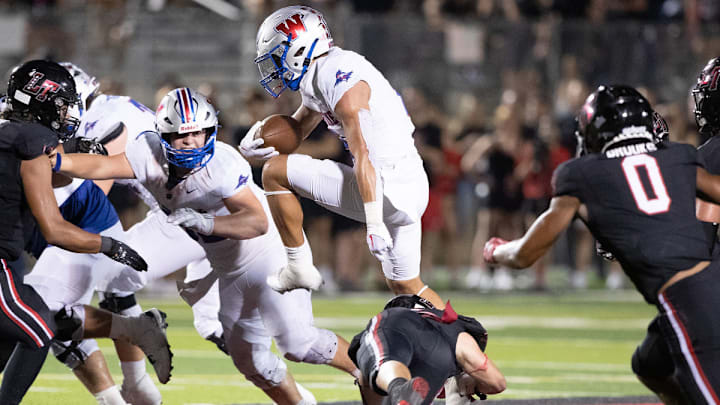 Westlake hurdles through the Lake Travis defense in a 2023 high school football game in Texas.