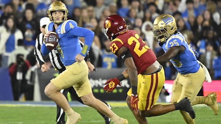 Nov 23, 2024; Pasadena, California, USA;  UCLA Bruins quarterback Ethan Garbers (4) scrambles out of the pocket chased by USC Trojans linebacker Desman Stephens II (23) during the first quarter at Rose Bowl. Mandatory Credit: Robert Hanashiro-Imagn Images
