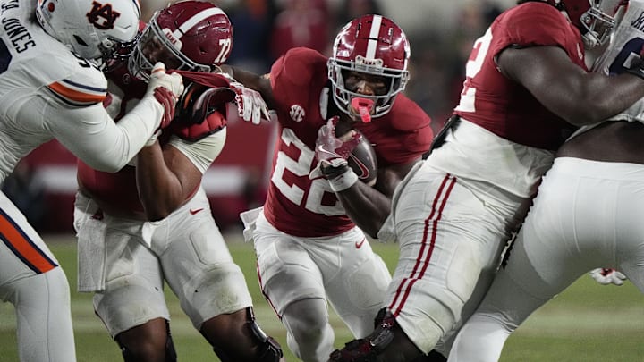 Nov 30, 2024; Tuscaloosa, Alabama, USA;  Alabama Crimson Tide running back Justice Haynes (22) runs behind offensive lineman Parker Brailsford (72) and offensive lineman Tyler Booker (52) against the Auburn Tigers during the second half at Bryant-Denny Stadium. Alabama won 28-14. Mandatory Credit: Gary Cosby Jr.-Imagn Images