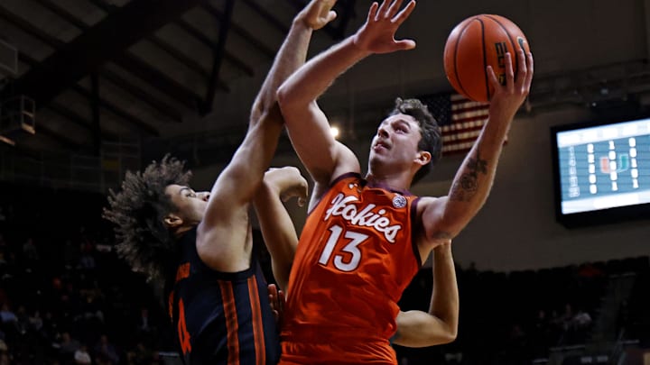 Jan 4, 2025; Blacksburg, Virginia, USA; Virginia Tech Hokies forward Ben Burnham (13) shoots the ball against Miami Hurricanes forward Isaiah Johnson-Arigu (4) during the first half at Cassell Coliseum. Mandatory Credit: Peter Casey-Imagn Images