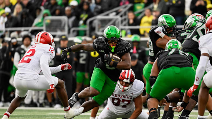 Oct 11, 2025; Eugene, Oregon, USA; Oregon Ducks running back Jordon Davison (0) runs the ball against Indiana Hoosiers defensive back Devan Boykin (12) and defensive lineman Mario Landino (97) during the second quarter at Autzen Stadium. Mandatory Credit: Troy Wayrynen-Imagn Images