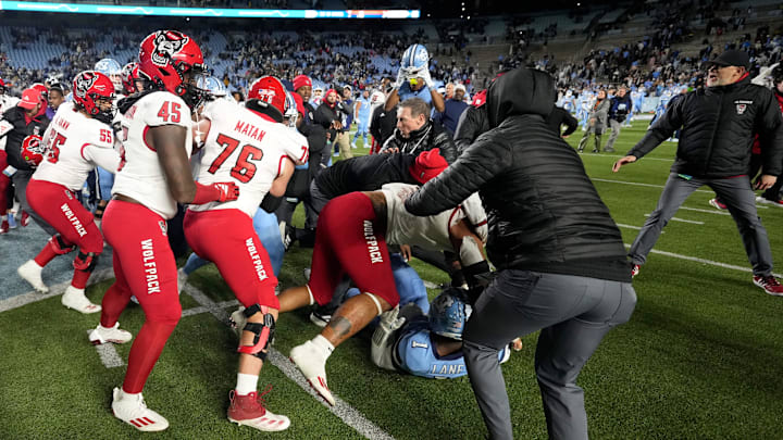 Nov 30, 2024; Chapel Hill, North Carolina, USA; North Carolina Tar Heels players and North Carolina State Wolfpack players fight as State tries to put a Wolfpack flag at midfield after the game at Kenan Memorial Stadium. Mandatory Credit: Bob Donnan-Imagn Images