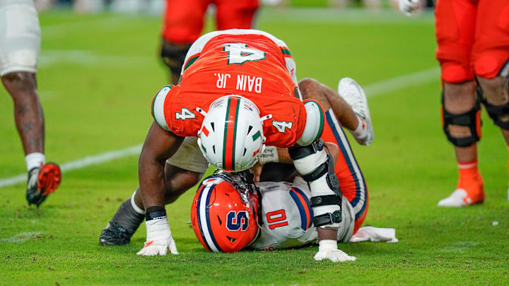 Nov 8, 2025; Miami Gardens, Florida, USA; Syracuse Orange quarterback Rickie Collins (10) is sacked by Miami Hurricanes defensive lineman Rueben Bain Jr. (4) during the fourth quarter at Hard Rock Stadium. Mandatory Credit: Jeff Romance-Imagn Images