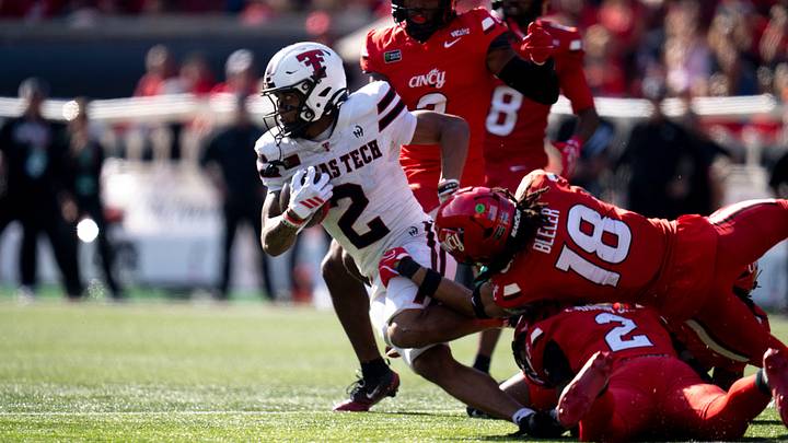 Cincinnati’s Jasper Beeler (18) and MJ Cannon (2) tackle Texas Tech wide receiver Kenny Johnson.