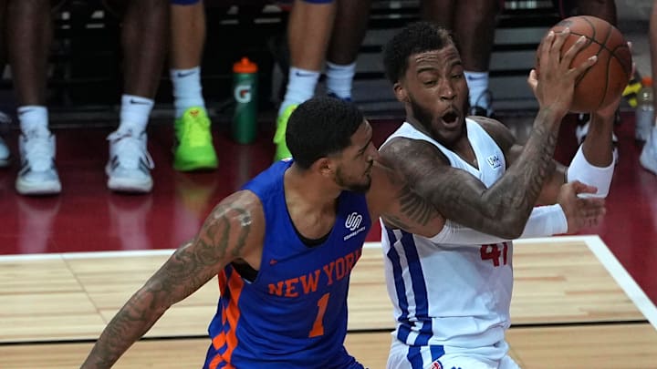 A Detroit Pistons forward protects the ball from the reach of New York Knicks forward Obi Toppin.