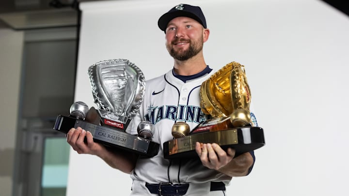 Seattle Mariners catcher Cal Raleigh poses with his Gold Glove and Platinum Glove trophies during media day Feb. 20 at Peoria Sports Complex.