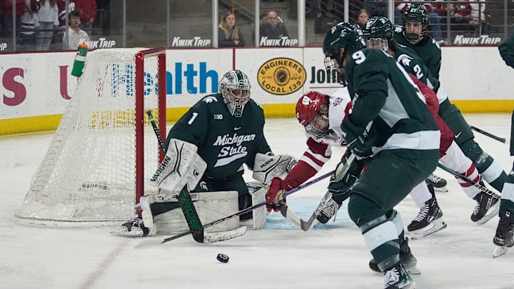 Wisconsin forward Cruz Lucius (51) is shoved by Michigan St. defensemen Patrick Geary (2) and Matt Basgall (9).