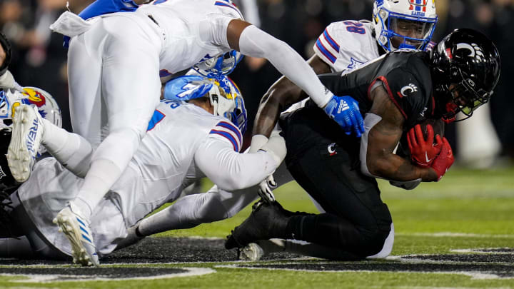 Cincinnati Bearcats running back Corey Kiner (21) is tackled while in possession of the ball by three Kansas Jayhawks during the NCAA college football game between the Cincinnati Bearcats and Kansas Jayhawks on Saturday, Nov. 25, 2023, at Nippert Stadium in Cincinnati. Kansas won 49-16.