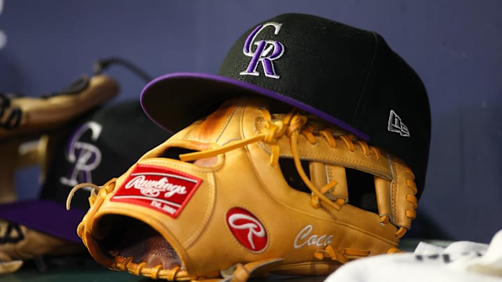 A detailed view of a Colorado Rockies hat and glove on the bench against the Atlanta Braves in the ninth inning at Truist Park.