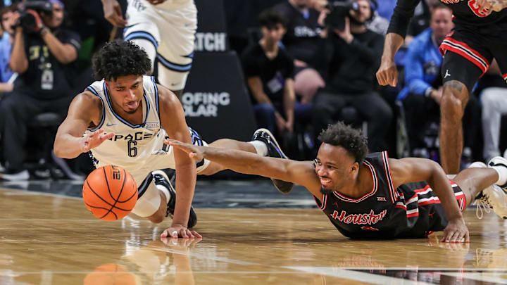 Jan 18, 2025; Orlando, Florida, USA; UCF Knights guard Dallan Coleman (6) and Houston Cougars guard L.J. Cryer (4) chase a loose ball during the second half at Addition Financial Arena. Mandatory Credit: Mike Watters-Imagn Images