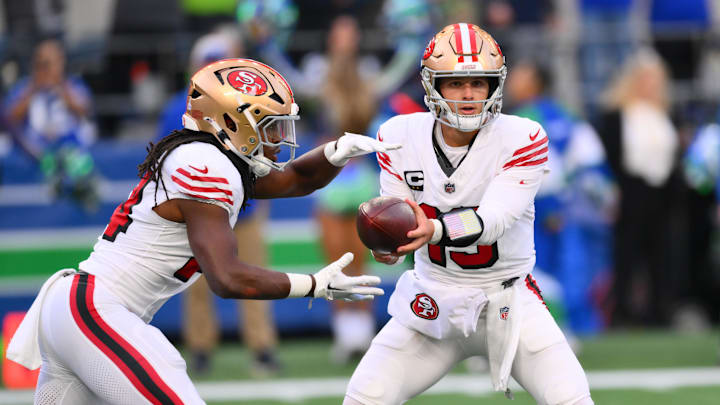 Oct 10, 2024; Seattle, Washington, USA; San Francisco 49ers quarterback Brock Purdy (13) hands the ball off to running back Jordan Mason (24) during the first half against the Seattle Seahawks at Lumen Field. Mandatory Credit: Steven Bisig-Imagn Images