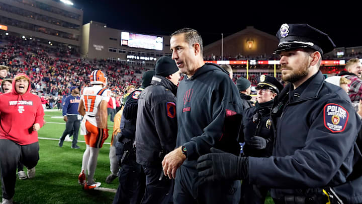 Nov 22, 2025; Madison, Wisconsin, USA; Wisconsin Badgers head coach Luke Fickell is escorted off the field as fans storm the field following a 27-10 win over the Illinois Fighting Illini at Camp Randall Stadium. Mandatory Credit: Kayla Wolf-Imagn Images