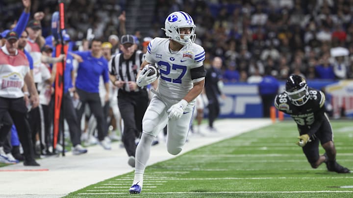 Dec 28, 2024; San Antonio, TX, USA; Brigham Young Cougars running back LJ Martin (27) runs with the ball past Colorado Buffaloes linebacker Brendan Gant (38) during the first quarter at Alamodome. Mandatory Credit: Troy Taormina-Imagn Images