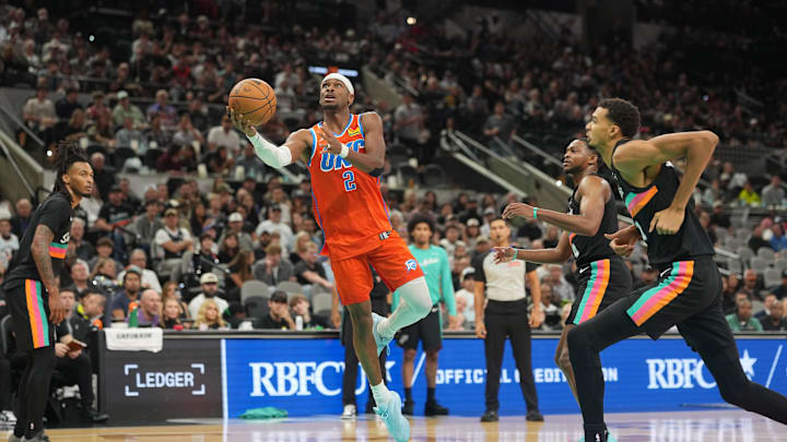 Dec 23, 2025; San Antonio, Texas, USA; Oklahoma City Thunder guard Shai Gilgeous-Alexander (2) drives to the basket between San Antonio Spurs forward Victor Wembanyama (1) and guard Stephon Castle (5) during the second half at Frost Bank Center. Mandatory Credit: Scott Wachter-Imagn Images