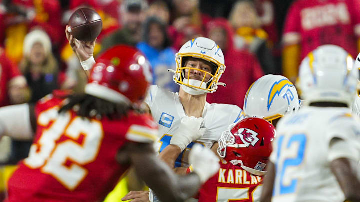 Dec 8, 2024; Kansas City, Missouri, USA; Los Angeles Chargers quarterback Justin Herbert (10) throws a pass as he is hit by Kansas City Chiefs defensive end George Karlaftis (56) during the first half at GEHA Field at Arrowhead Stadium. Mandatory Credit: Jay Biggerstaff-Imagn Images