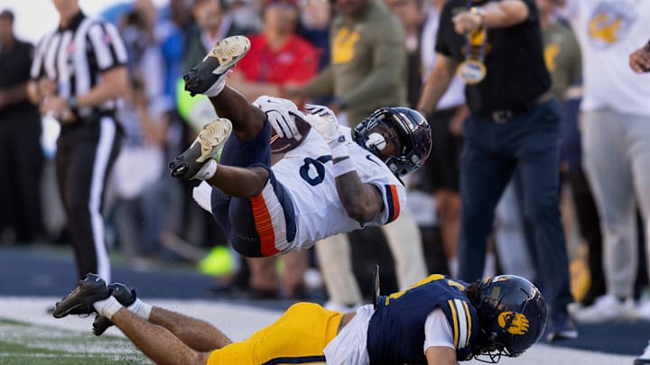 Nov 1, 2025; Berkeley, California, USA; California Golden Bears defensive back Brent Austin (4) upends Virginia Cavaliers wide receiver Cam Ross (6) on a short pass during the fourth quarter at California Memorial Stadium. Mandatory Credit: D. Ross Cameron-Imagn Images