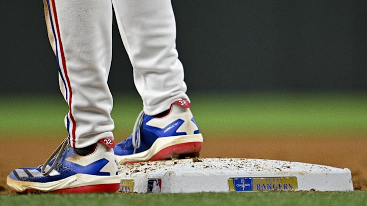 Mar 31, 2024; Arlington, Texas, USA; A view the shoes of Texas Rangers right fielder Evan Carter (32) and first base and the Rangers World Champions logo during the game against the Chicago Cubs at Globe Life Field. Mandatory Credit: Jerome Miron-Imagn Images