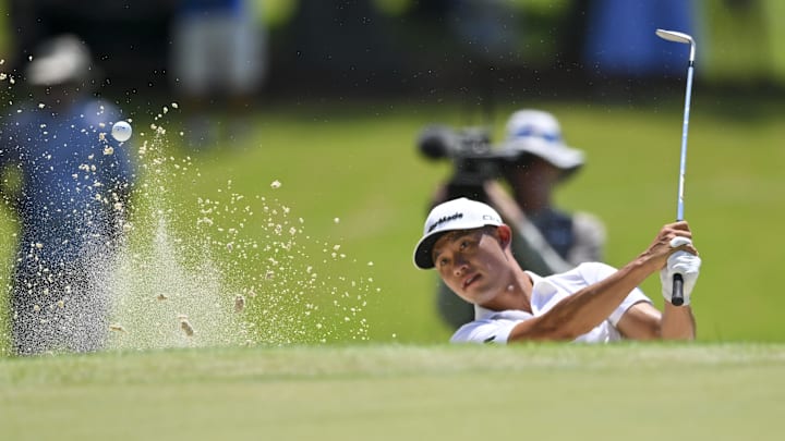 Collin Morikawa hits out of the bunker on the second hole