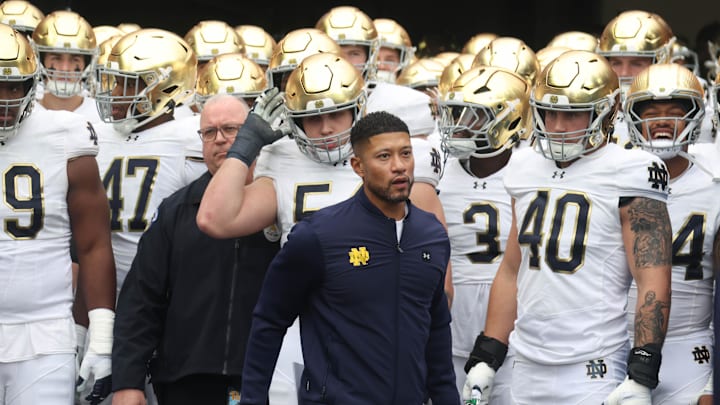 Nov 15, 2025; Pittsburgh, Pennsylvania, USA;  Notre Dame Fighting Irish head coach Marcus Freeman (middle) leads the team onto the field to play the Pittsburgh Panthers at Acrisure Stadium. Mandatory Credit: Charles LeClaire-Imagn Images