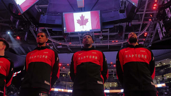 Mar 23, 2025; Toronto, Ontario, CAN; Toronto Raptors center Orlando Robinson (left) and forward RJ Barrett (center) and forward Garrett Temple (right) during the national anthem before a game against the San Antonio Spurs at Scotiabank Arena. Mandatory Credit: John E. Sokolowski-Imagn Images