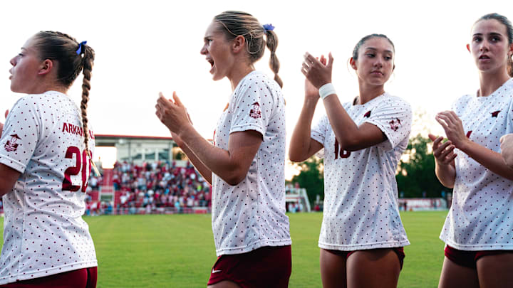 Arkansas soccer players cheer on teammates before a match.