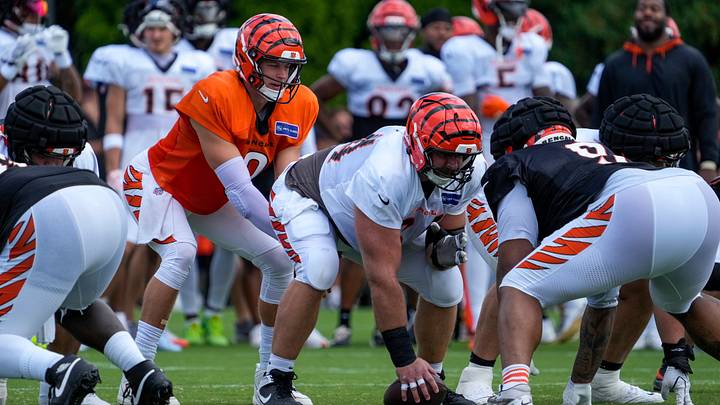 Cincinnati Bengals quarterback Joe Burrow (9) takes a snap from center Ted Karras (64) during practice at the Paycor Stadium practice facility in downtown Cincinnati on Monday, Aug. 3, 2026.