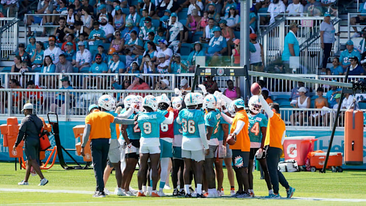 Miami Dolphins defensive backs huddle in front of a sold out crowd at training camp at Baptist