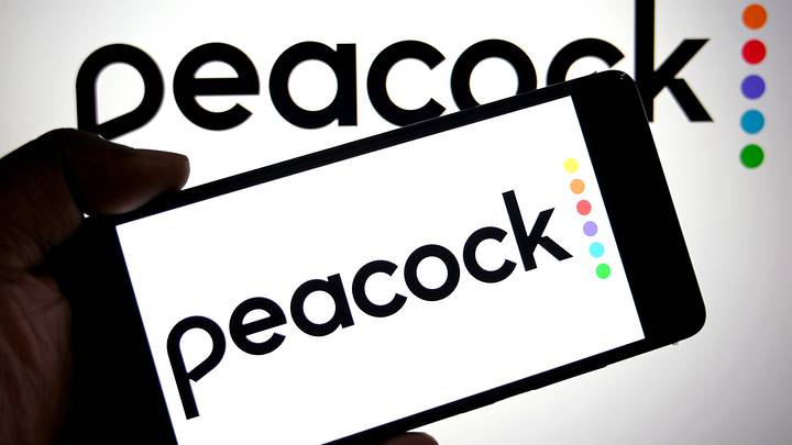 In this photo illustration, a Peacock logo is seen displayed on a smartphone and in the background. In this photo illustration, a Peacock logo is seen displayed on a smartphone and in the background.