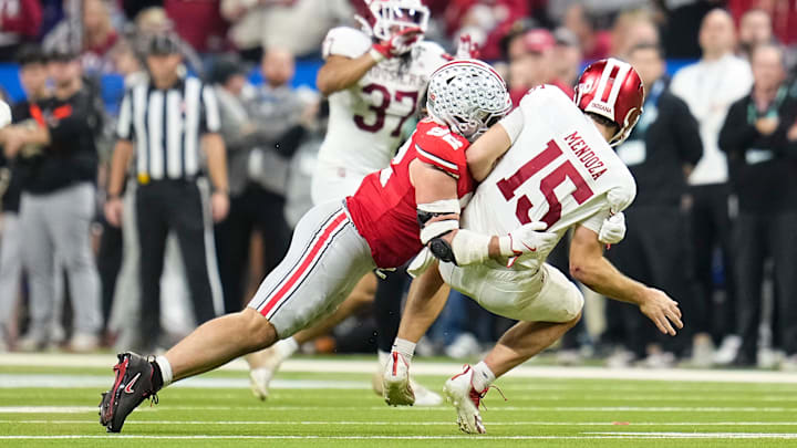 Indiana Hoosiers quarterback Fernando Mendoza (15) gets off a pass as he's hit by Ohio State Buckeyes defensive end Caden Curry (92) during the first half of the Big Ten Conference championship game at Lucas Oil Stadium in Indianapolis on Dec. 6, 2025.