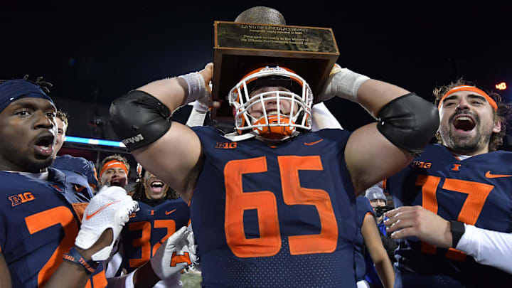 Nov 27, 2021; Champaign, Illinois, USA;  Illinois Fighting Illini offensive lineman Doug Kramer (65) lifts the Land of Lincoln trophy after defeating the Northwestern Wildcats at Memorial Stadium. Mandatory Credit: Ron Johnson-Imagn Images