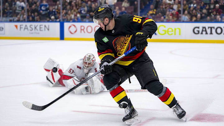 Oct 28, 2024; Vancouver, British Columbia, CAN; Vancouver Canucks forward Daniel Sprong (91) and Carolina Hurricanes goalie Pyotr Kochetkov (52) look at the flying puck after Kocketkov dove to poke check Sprong during the third period at Rogers Arena. Mandatory Credit: Bob Frid-Imagn Images