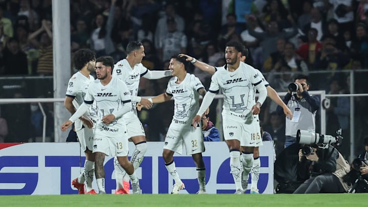 Leo Suárez (center) is mobbed by teammates after his goal put UNAM ahead of América, helping the Pumas defeat the defending Liga MX champs in a Matchday 16 contest.
