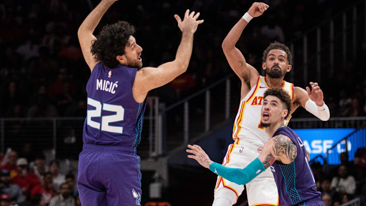 Oct 25, 2024; Atlanta, Georgia, USA; Atlanta Hawks guard Trae Young (11) makes a pass against Charlotte Hornets guard Vasilije Micic (22) and guard LaMelo Ball (1) during the fourth quarter at State Farm Arena. Mandatory Credit: Jordan Godfree-Imagn Images