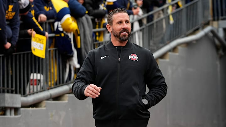 Ohio State Buckeyes offensive coordinator Brian Hartline laughs after hearing jeers as he walks onto the field prior to the NCAA football game against the Michigan Wolverines at Michigan Stadium in Ann Arbor, Mich. on Nov. 29, 2025.