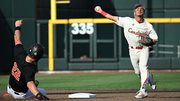 Jun 13, 2025; Omaha, Neb, USA; Louisville Cardinals shortstop Alex Alicea (0) complete a double play ahead of the slide from Oregon State Beavers first baseman Jacob Krieg (22) during the third inning at Charles Schwab Field. Mandatory Credit: Steven Branscombe-Imagn Images