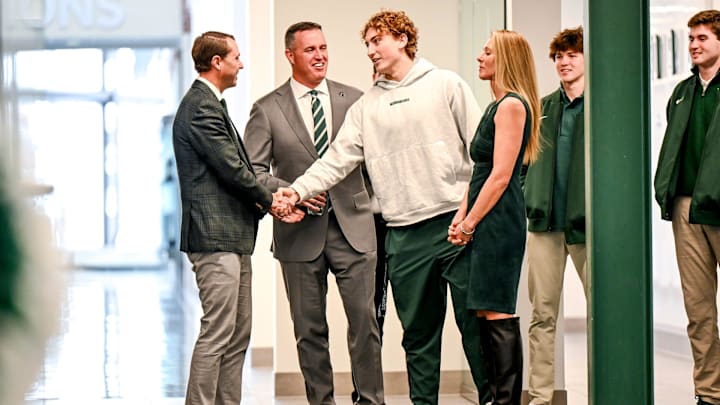 Michigan State's new football coach Pat Fitzgerald, center, and MSU Athletic Director J Batt, left, meets with Spartans quarterback Alessio Milivojevic, right, while waiting for Fitzgerald's introductory press conference to start on Tuesday, Dec. 2, 2025, at the Tom Izzo Football Building in East Lansing. Michigan State's new football coach Pat Fitzgerald, center, and MSU Athletic Director J Batt, left, meets with Spartans quarterback Alessio Milivojevic, right, while waiting for Fitzgerald's introductory press conference to start on Tuesday, Dec. 2, 2025, at the Tom Izzo Football Building in East Lansing.