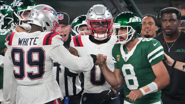Sep 19, 2024; East Rutherford, New Jersey, USA;  New York Jets quarterback Aaron Rodgers (8)  bumps fists with New England Patriots defensive end Keion White (99) after Rogers was tackled on the sidelines by White in the second half at MetLife Stadium.