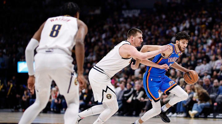 Dec 29, 2023; Denver, Colorado, USA; Oklahoma City Thunder forward Chet Holmgren (7) controls the ball against Denver Nuggets center Nikola Jokic (15) as forward Peyton Watson (8) defends in the first quarter at Ball Arena. Mandatory Credit: Isaiah J. Downing-Imagn Images