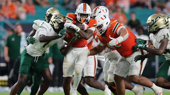 Sep 13, 2025; Miami Gardens, Florida, USA; Miami Hurricanes running back Mark Fletcher Jr. (4) carries the football against South Florida Bulls cornerback Ben Knox (1) during the third quarter at Hard Rock Stadium. Mandatory Credit: Sam Navarro-Imagn Images